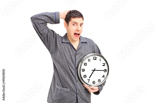 Photo: Shocked male in pijamas holding an alarm clock Shocked male in pijamas holding an alarm clock