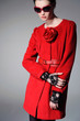 Photo: Studio portrait of a beautiful young woman in red coat Studio portrait of a beautiful young woman in red coat