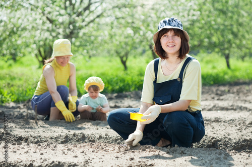 Photo: women with child works at vegetables garden women with child works at vegetables garden