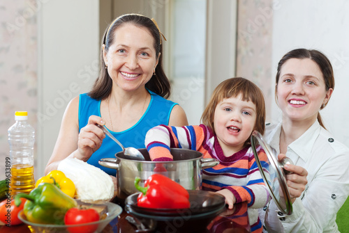 Photo: Mature woman and adult daughter with girl cook lunch Mature woman and adult daughter with girl cook lunch