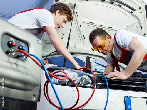 Photo: Two car mechanics check the air handling unit of a car Two car mechanics check the air handling unit of a car
