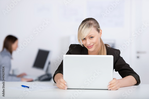 Photo: lächelnde frau mit laptop im büro lächelnde frau mit laptop im büro