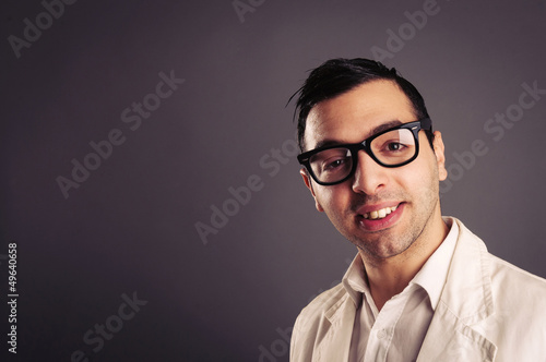 Photo: Funny portrait of young nerd with eyeglasses on grey background. Funny portrait of young nerd with eyeglasses on grey background.