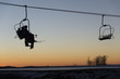 Skiers and snowboarders on chair lift at sunset