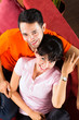 Asian couple at home on sofa