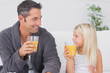 Father and his daughter drinking glass of orange juice