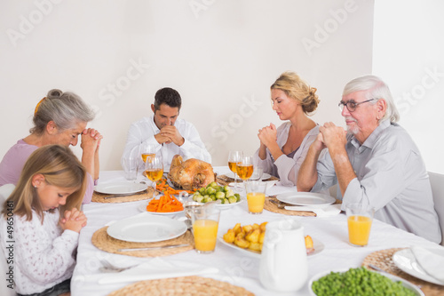 Photo: Family saying grace before eating a turkey Family saying grace before eating a turkey