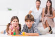 Happy siblings playing board game on floor