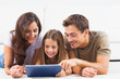 Family lying on a carpet with tablet