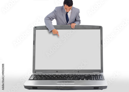 Photo: Businessman pointing down to blank laptop screen Businessman pointing down to blank laptop screen