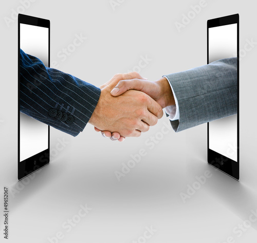 Photo: Businessmen shaking hands from digital tablets Businessmen shaking hands from digital tablets