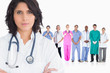 Woman doctor standing arms crossed in front of her team