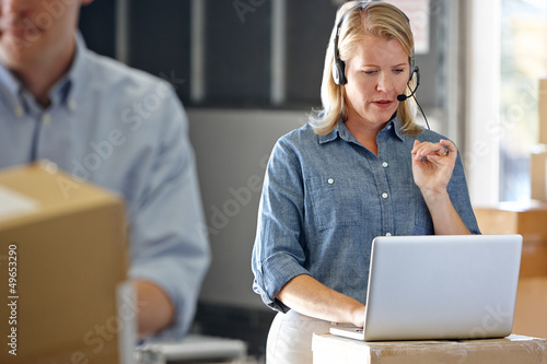 Photo: Female Manager Using Headset In Distribution Warehouse Female Manager Using Headset In Distribution Warehouse
