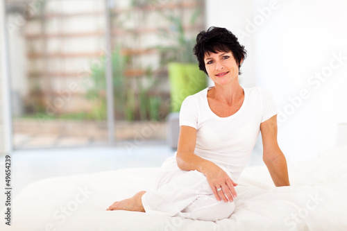 Photo: beautiful middle aged woman sitting on bed beautiful middle aged woman sitting on bed