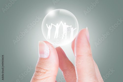 Photo: Hand with the paper cut of the family in bubble Hand with the paper cut of the family in bubble