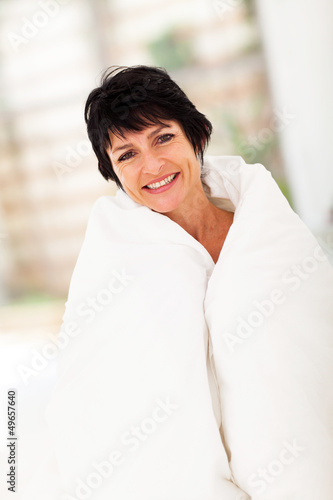 Photo: cute middle aged woman covered by duvet at home cute middle aged woman covered by duvet at home