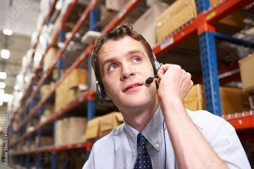 Photo: Businessman Using Headset In Distribution Warehouse Businessman Using Headset In Distribution Warehouse