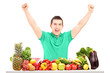 Excited man raising hands and posing with a pile of fruit and ve