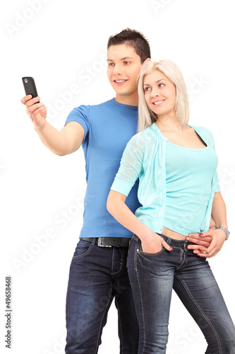 Photo: Attractive young couple taking a photo with a mobile phone Attractive young couple taking a photo with a mobile phone