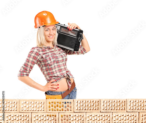 Photo: Female construction worker with radio posing next to a pile od b Female construction worker with radio posing next to a pile od b
