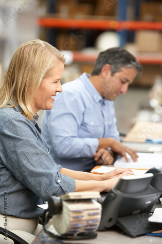 Photo: Business Colleagues Working At Desk In Warehouse Business Colleagues Working At Desk In Warehouse