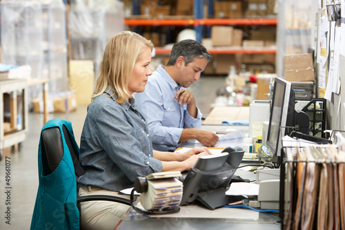 Photo: Business Colleagues Working At Desk In Warehouse Business Colleagues Working At Desk In Warehouse