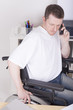 young busy man in wheelchair with phone