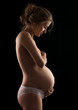 Photo: Young pregnant woman over black background Young pregnant woman over black background