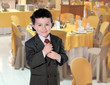 Elegant little boy clutching his tie in a restaurant
