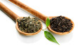 Dry tea with green leaves in wooden spoons, isolated on white