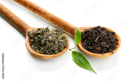 Photo: Dry tea with green leaves in wooden spoons, isolated on white Dry tea with green leaves in wooden spoons, isolated on white