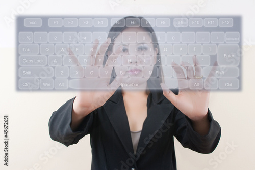 Photo: business lady pushing transparent keyboard on the whiteboard. business lady pushing transparent keyboard on the whiteboard.