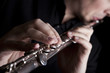 professional flutist musician playing flute on black background