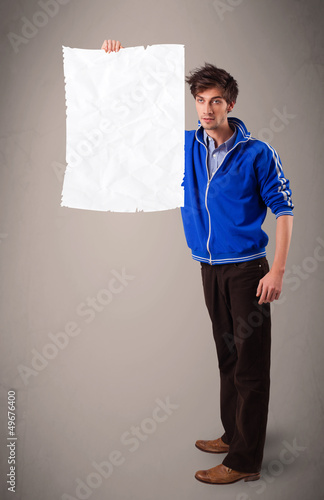 Photo: Young boy holding crumpled white paper copy space Young boy holding crumpled white paper copy space