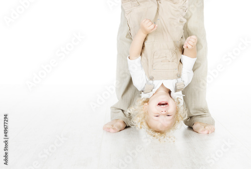 Photo: Child standing head over heels. Funny up portrait. Parent legs. Child standing head over heels. Funny up portrait. Parent legs.