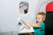 little boy with touch pad on plane in flight