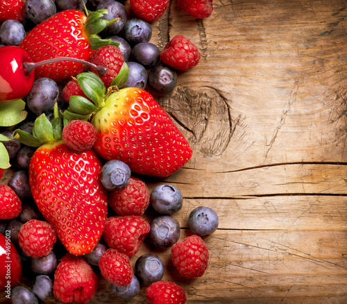 Photo: Berries on Wooden Background. Organic Berry over Wood Berries on Wooden Background. Organic Berry over Wood