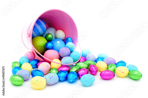 Photo: Pink Easter pail spilling colorful chocolate eggs and candy Pink Easter pail spilling colorful chocolate eggs and candy
