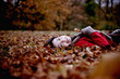 A woman lying on the ground hold an autumn leaf
