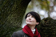 A woman standing next to a tree in autumn time, looking up