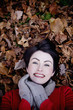 A woman lying amongst autumn leaves