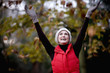 A woman catching falling autumn leaves