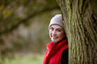 A woman leaning against a tree in autumn time, smiling