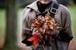A woman holding a handful of autumn leaves