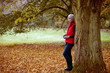 A woman standing next to a tree in autumn time