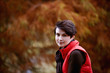 A woman sitting on a fence in autumn time, close up