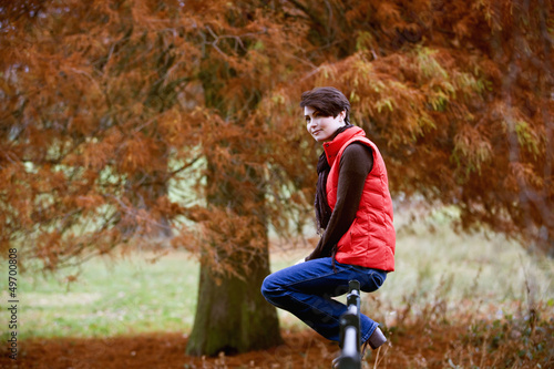 Photo: A woman sitting on a fence in autumn time A woman sitting on a fence in autumn time