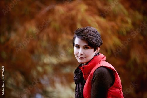 Photo: A woman sitting on a fence in autumn time, close up A woman sitting on a fence in autumn time, close up