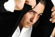 Portrait of a serious young man making headscarf with his jacket