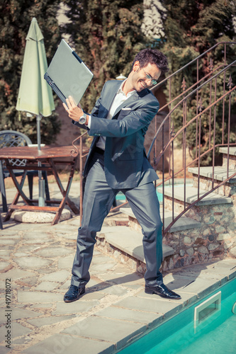 Photo: Angry Businessman with Computer next to Swimming Pool Angry Businessman with Computer next to Swimming Pool